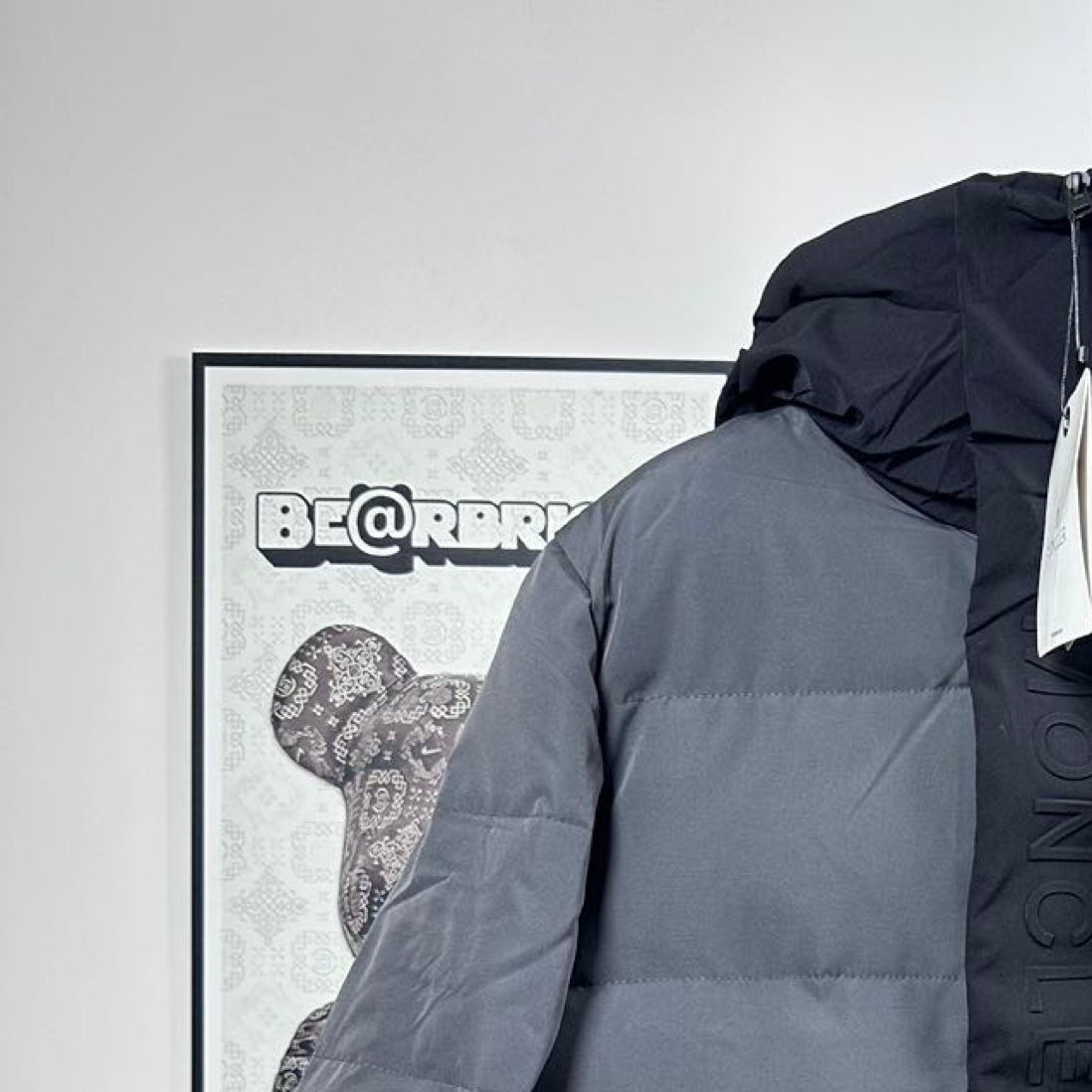 Moncler puffer jacket shoulder and hood detail, dark gray, with visible quilting lines