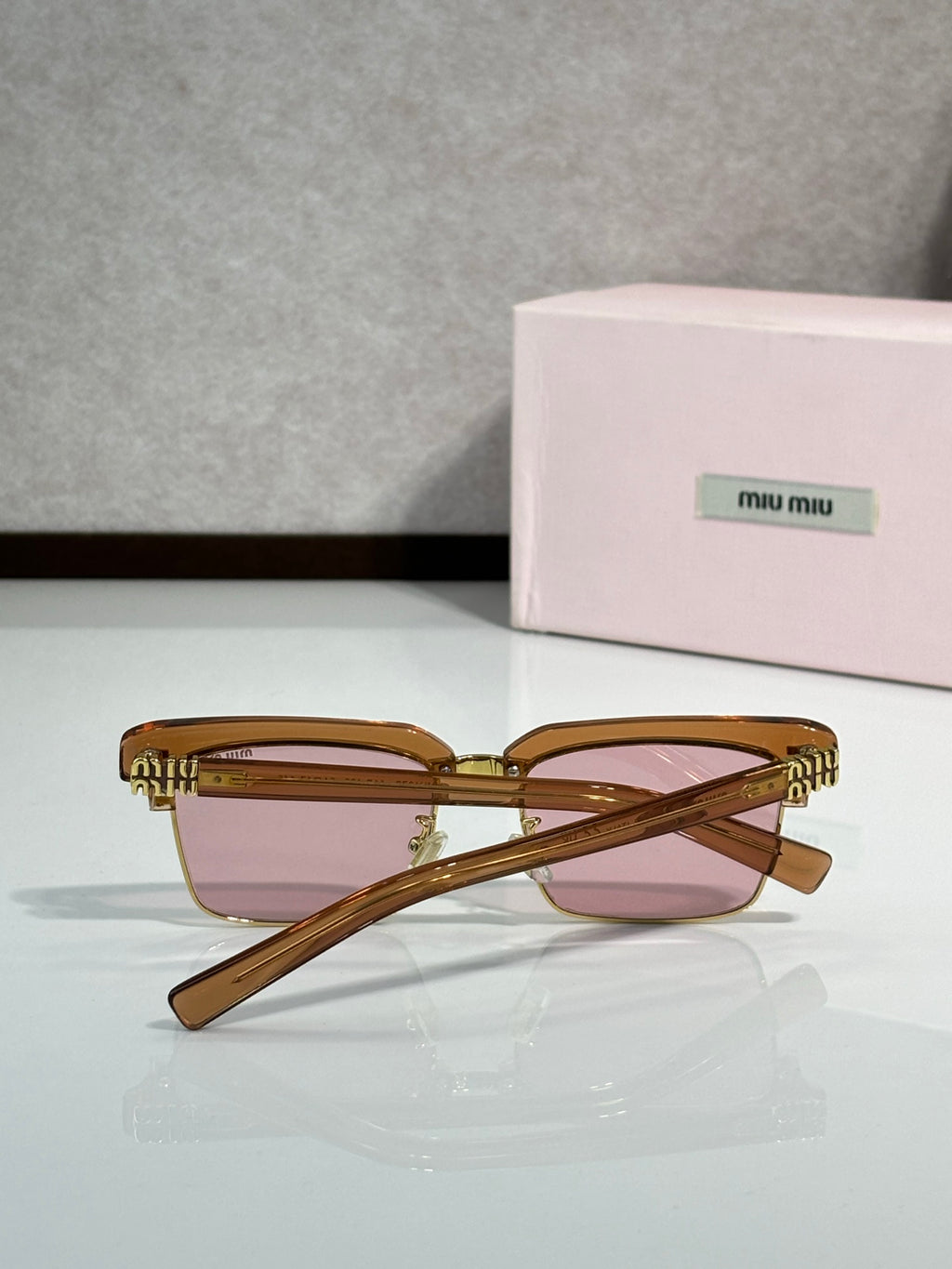 Square sunglasses with tortoiseshell frame, pink tinted lenses, gold accents, angled temples