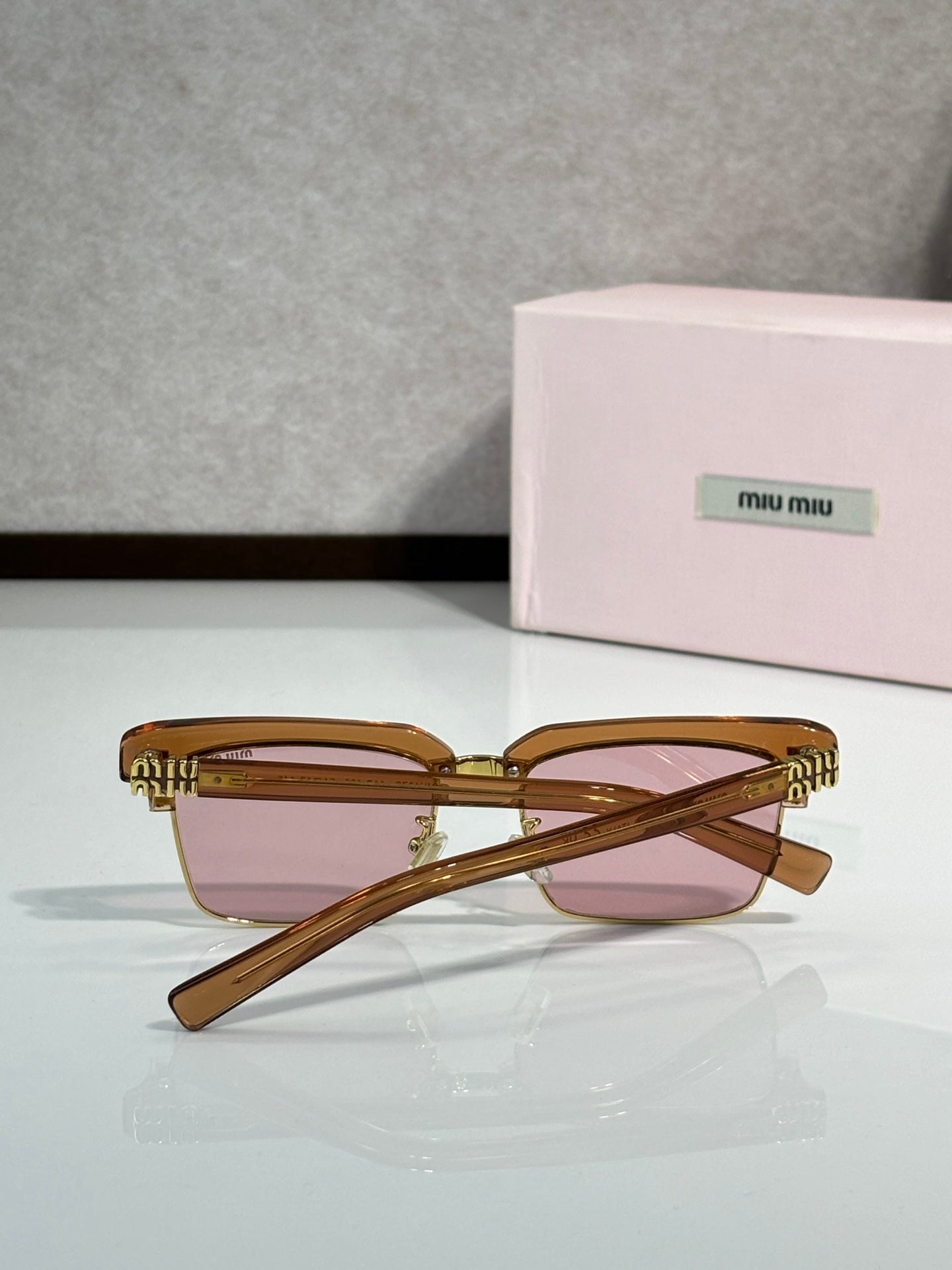 Square sunglasses with tortoiseshell frame, pink tinted lenses, gold accents, angled temples