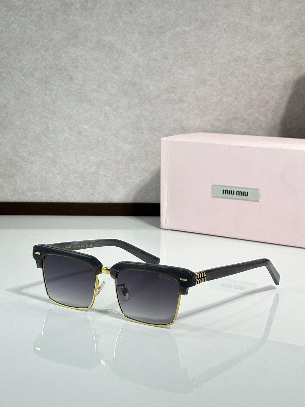 Square sunglasses with black frame and gold hinges, dark blue tinted lenses, slim temples