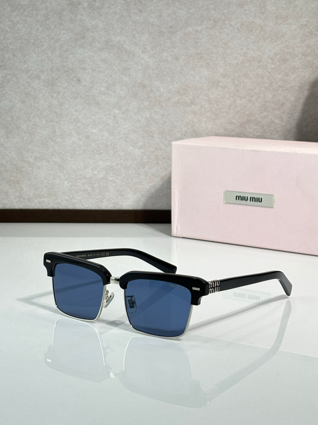 Square sunglasses with black frame and gold accents, blue tinted lenses, slim temples