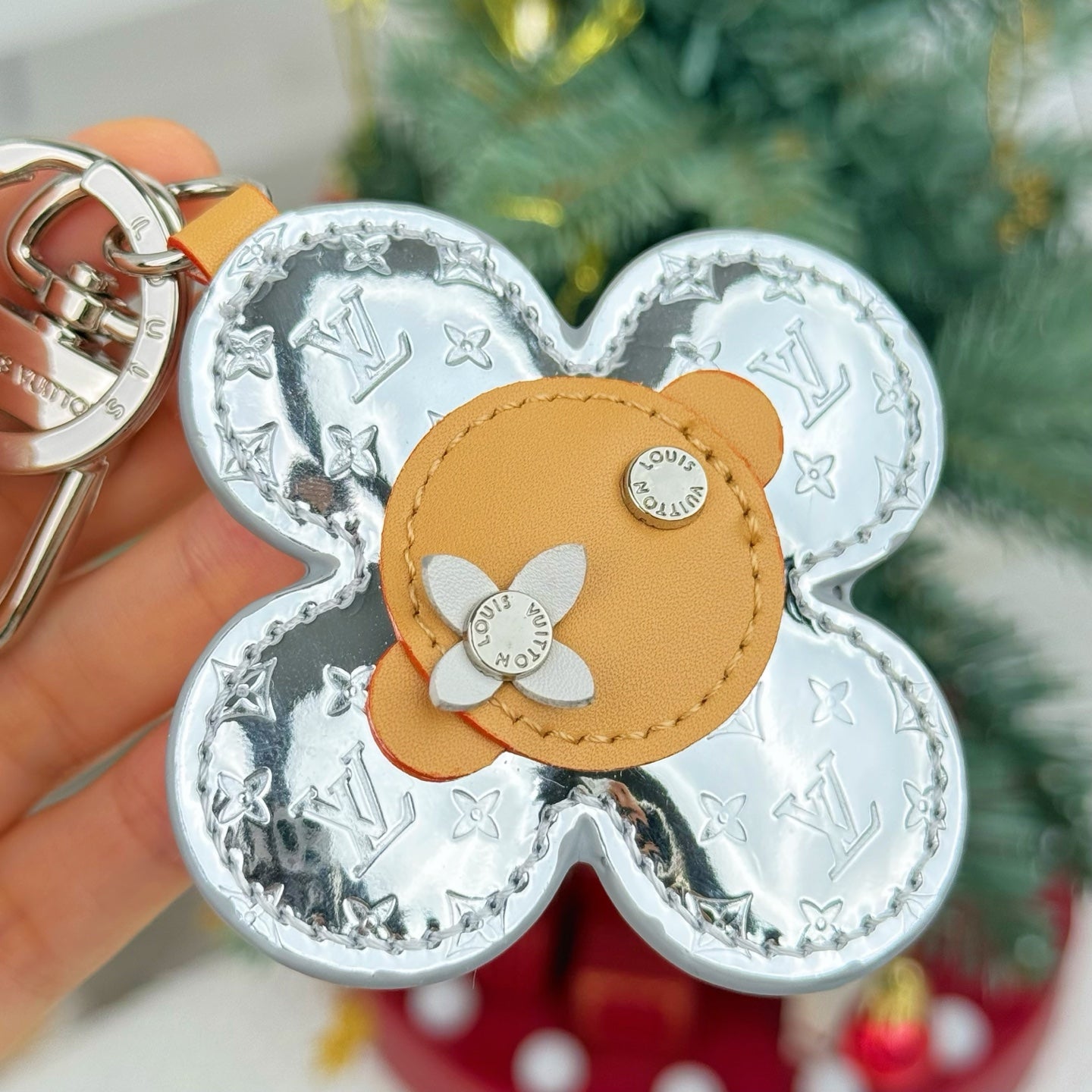 Close-up Louis Vuitton floral charm keyring with silver monogram and tan center