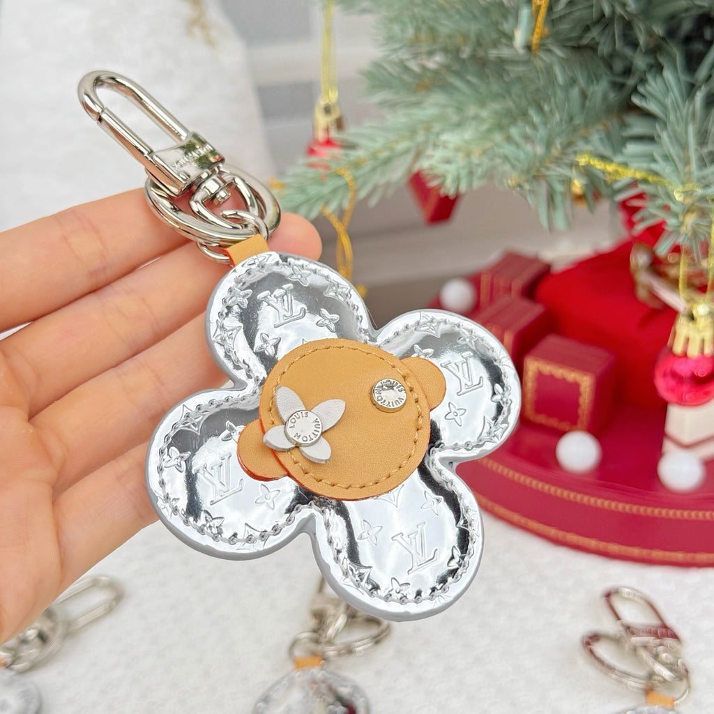 Louis Vuitton floral charm keyring held in hand with silver monogram and tan center