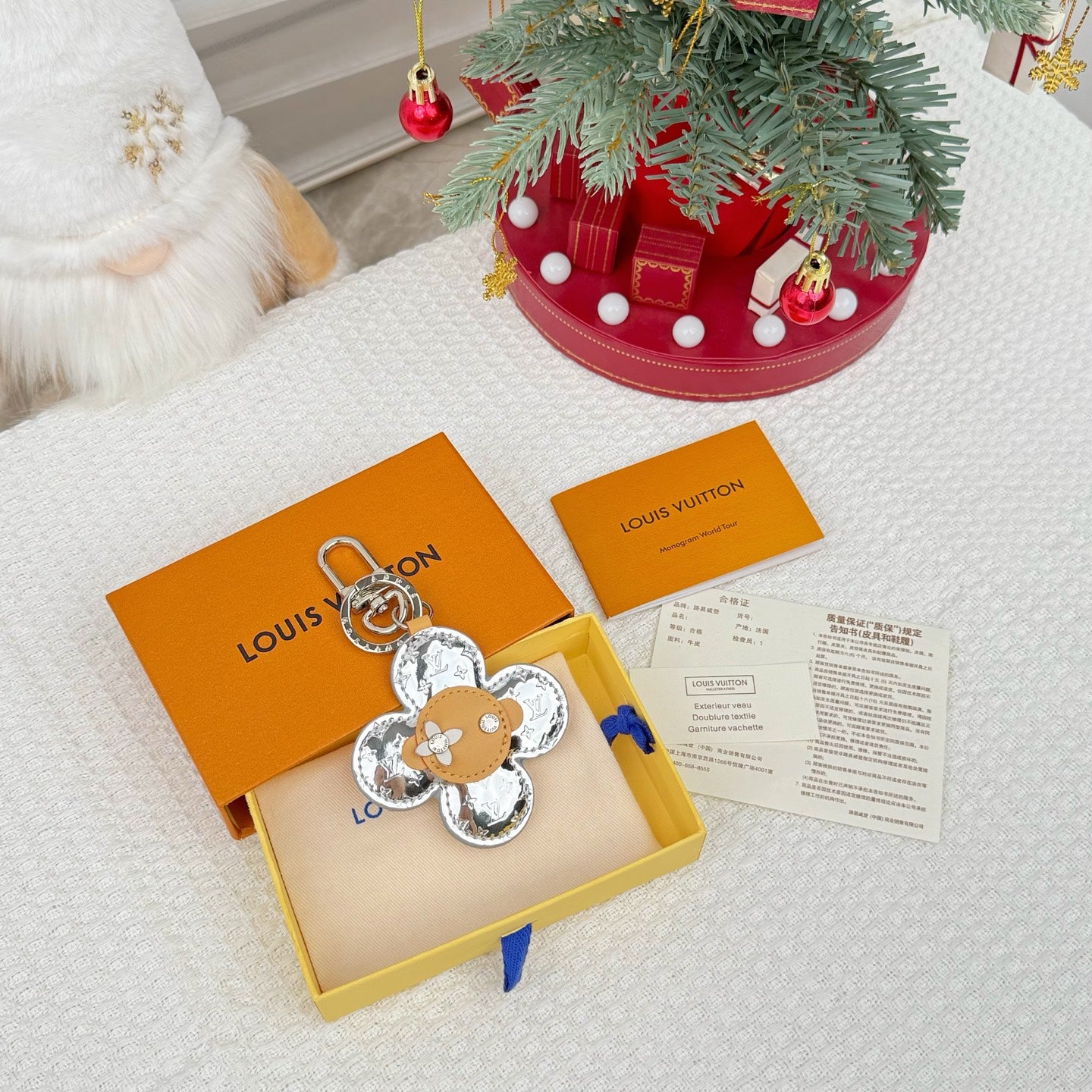 Flower-shaped keychain with silver monogram petals and tan leather center in a gift box