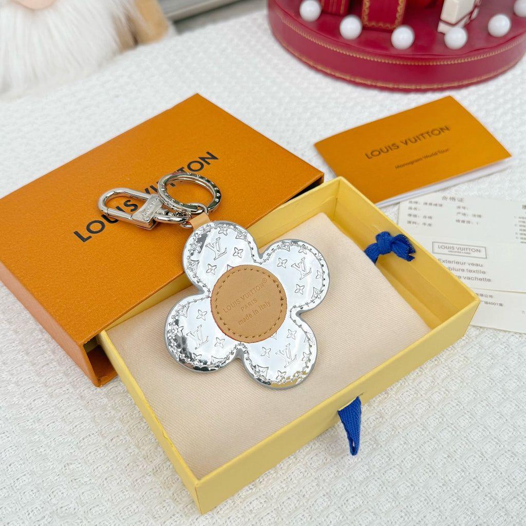 Flower-shaped keychain with silver monogram petals and tan leather center on a key ring