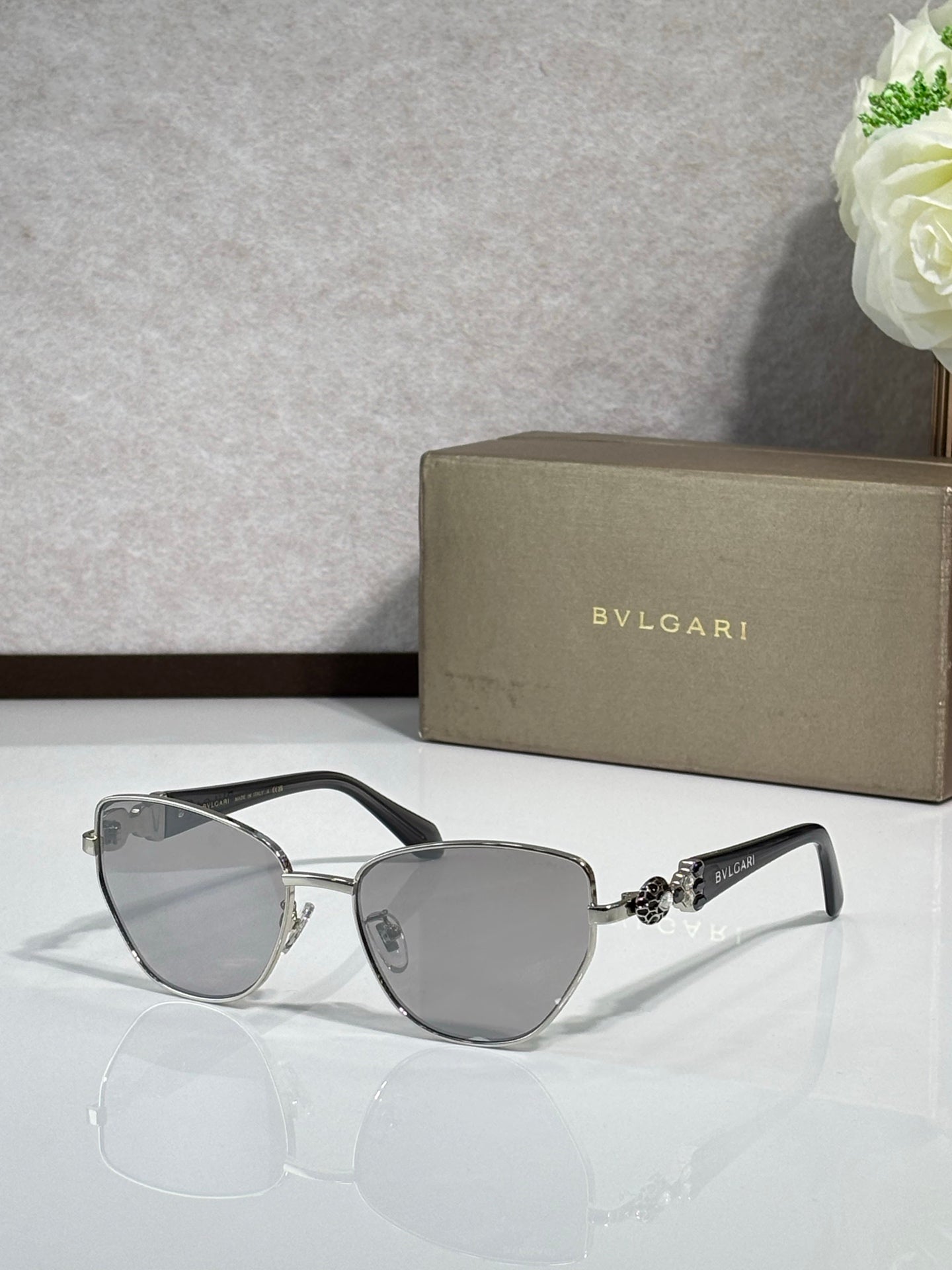 Gray cat-eye sunglasses with gold metal accents and gray gradient lenses.