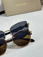 Gold cat-eye sunglasses with blue gradient lenses and BVLGARI logo on temple.
