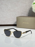 Black cat-eye sunglasses with gold metal accents and dark gradient lenses.
