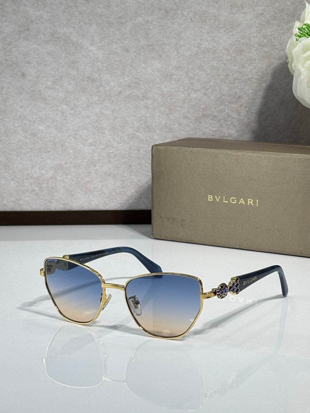 Blue cat-eye sunglasses with gold metal accents and blue gradient lenses.