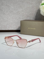 Pink/red cat-eye sunglasses with gold metal accents and soft pink gradient lenses.