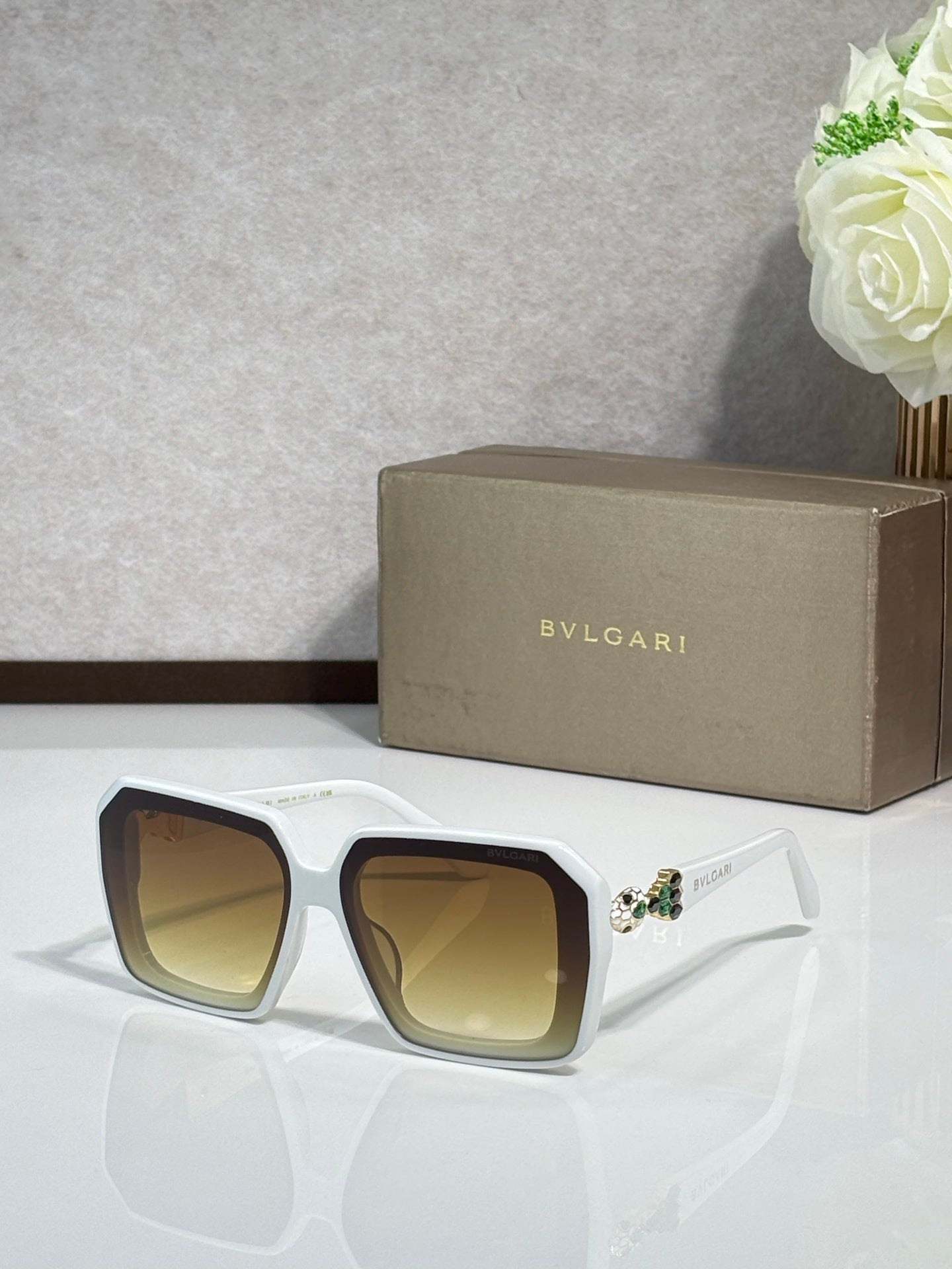Bvlgari sunglasses with white frames and yellow-tinted lenses, jeweled temple detail.