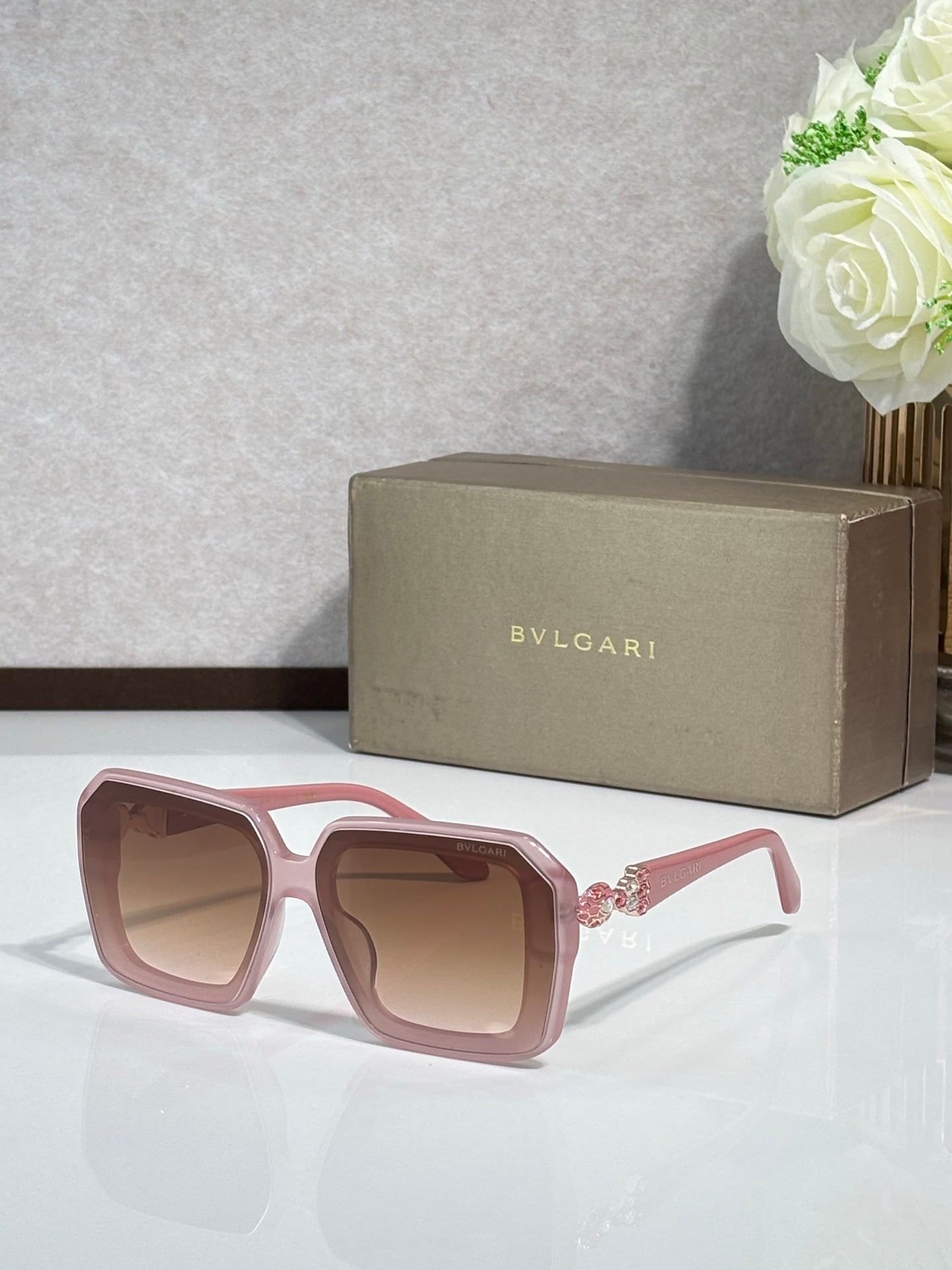 Bvlgari sunglasses with pink frames and tinted lenses, front view with jeweled temple accents.