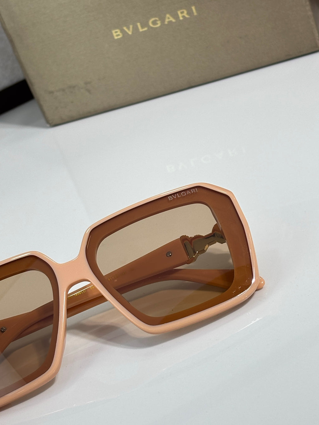 Bvlgari sunglasses with rose-gold frames and tinted lenses, close-up side profile.