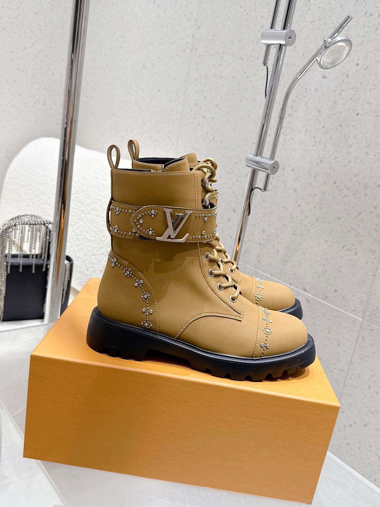 Tan lace-up ankle boot with front logo band and jeweled stud details