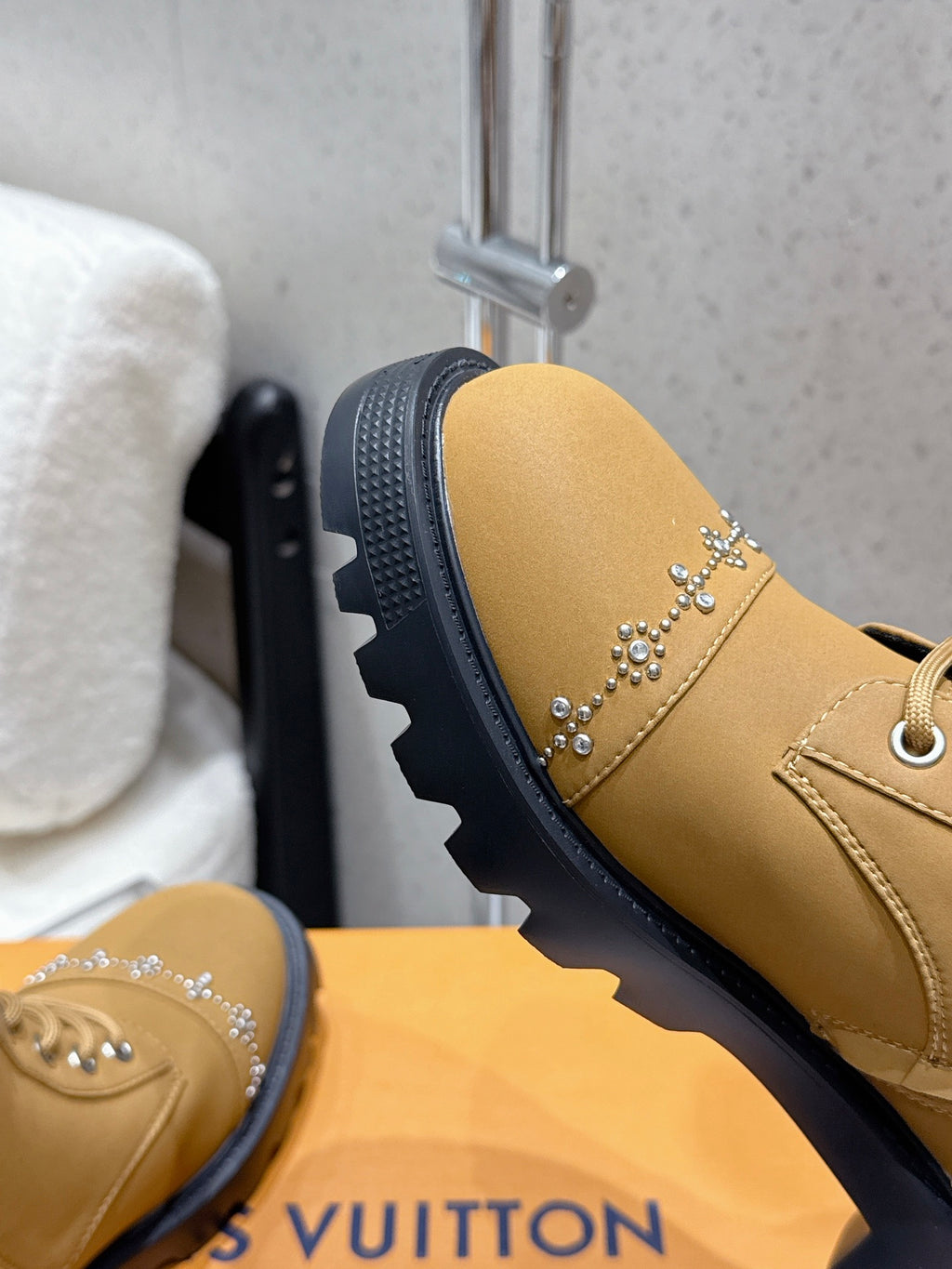 Tan ankle boot side view with studded strap and textured black sole