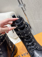 Black studded lace-up boot held by hand; lace and stud rows visible