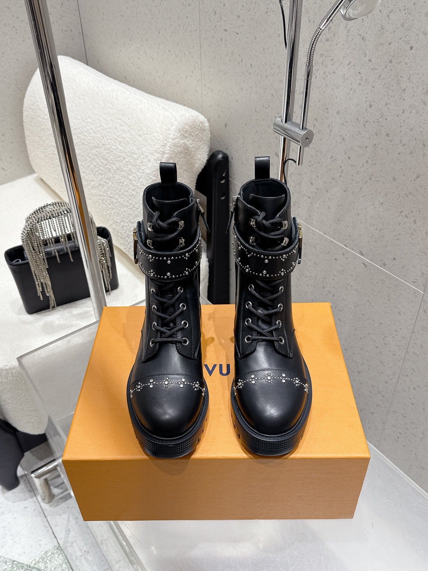Pair of black studded lace-up boots on a tan box