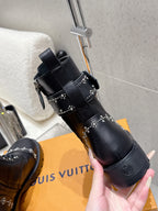 Hand holding black studded combat boots; side buckle and eyelets visible