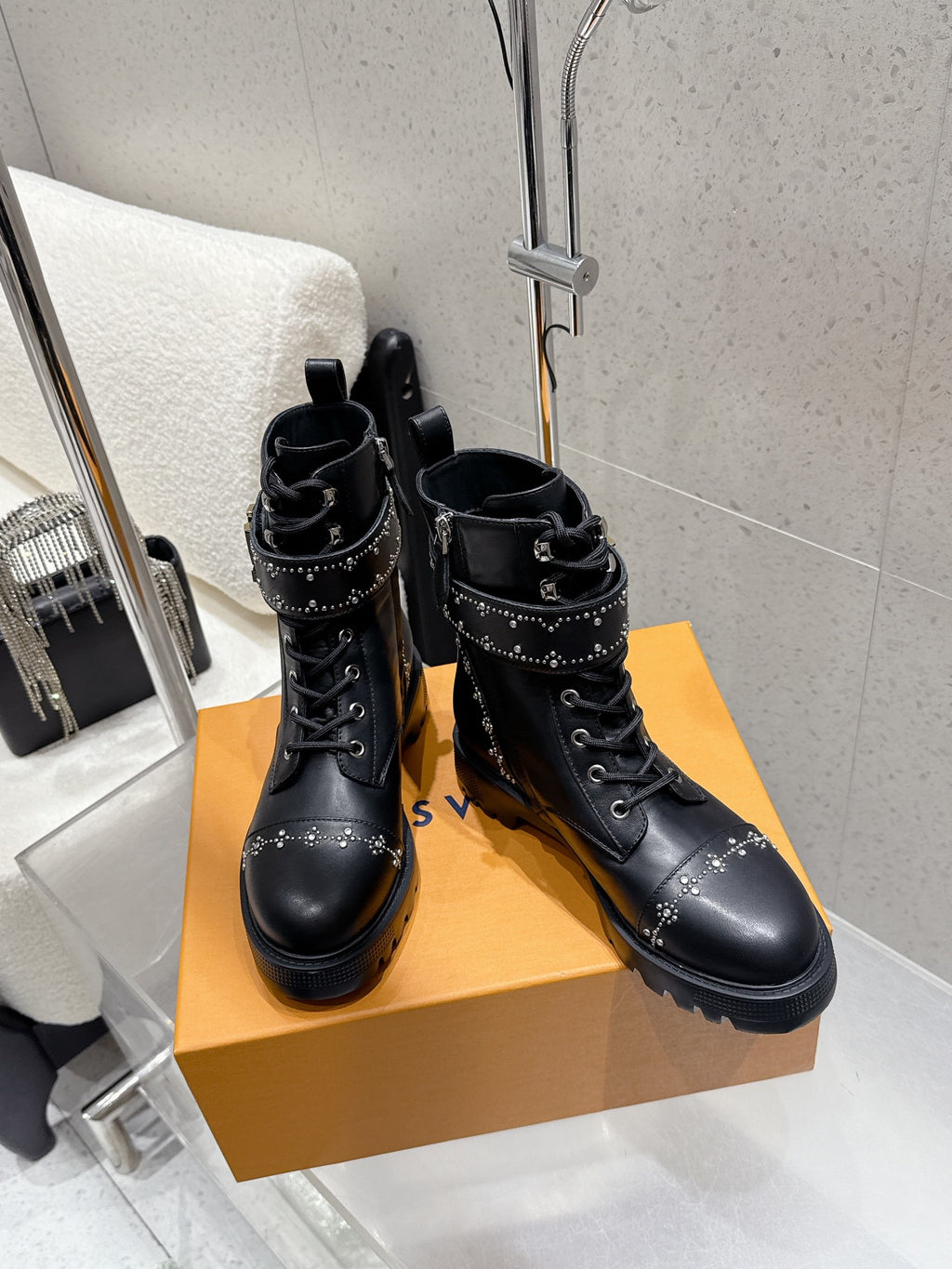 Two black lace-up boots with studded straps and chunky lug soles