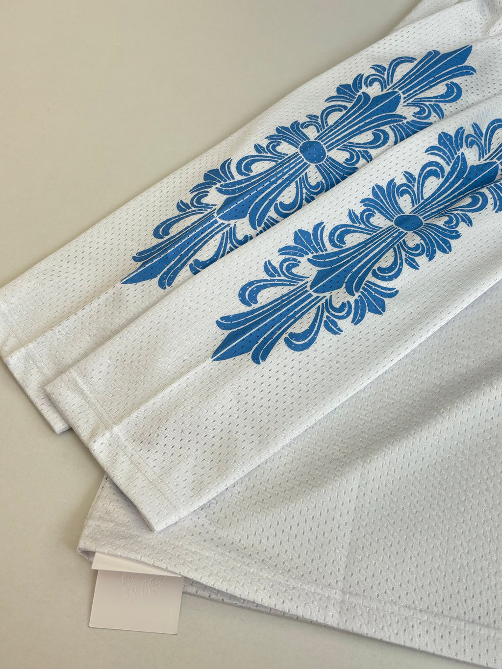 White long-sleeve jersey sleeve close-up with blue floral stripe graphic