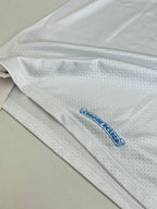 White long-sleeve jersey fabric close-up with small blue logo near hem