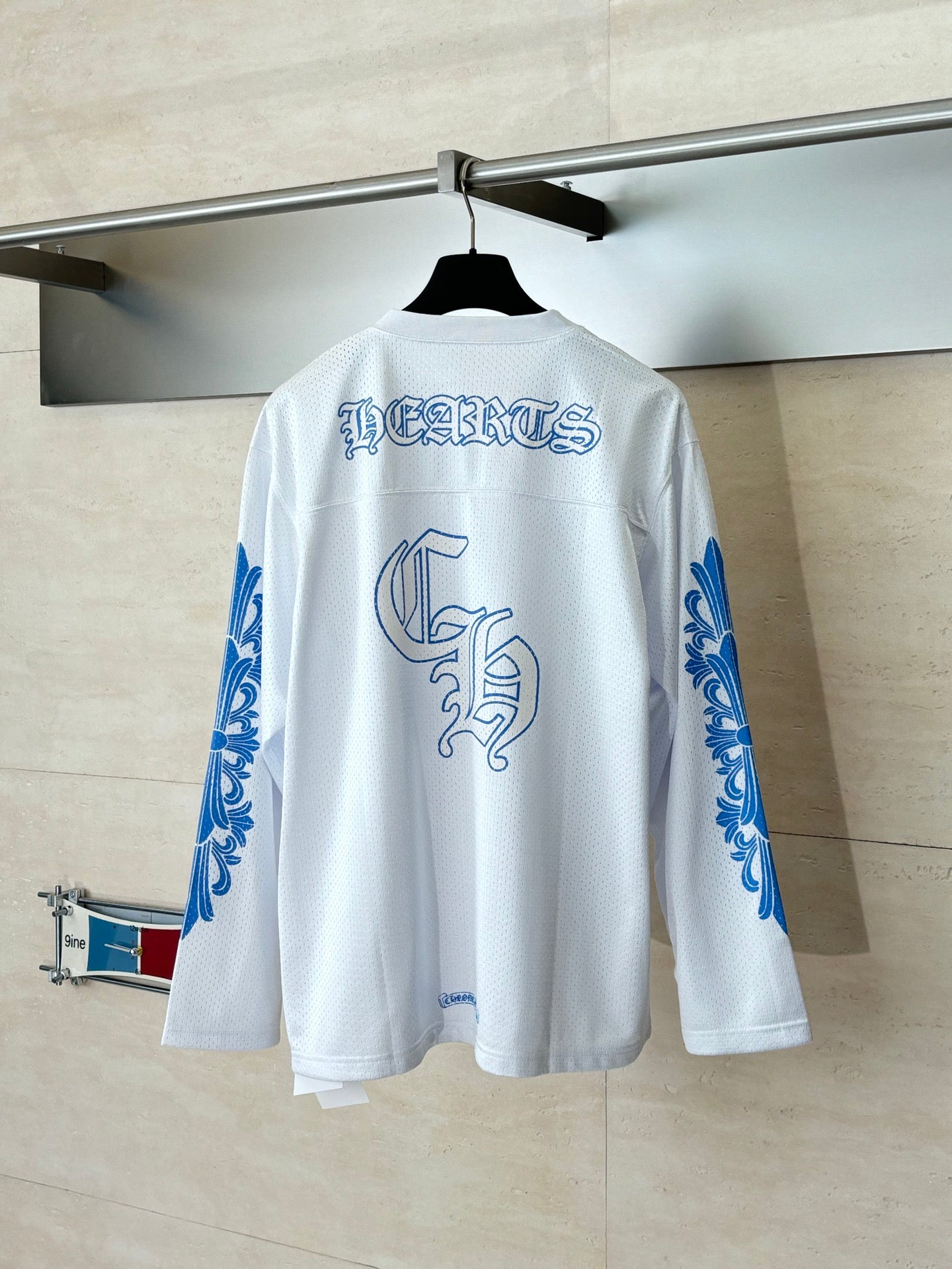 White long-sleeve V-neck jersey, back view with blue text and crest graphic