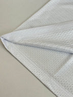 White long-sleeve jersey fabric close-up with subtle textured pattern