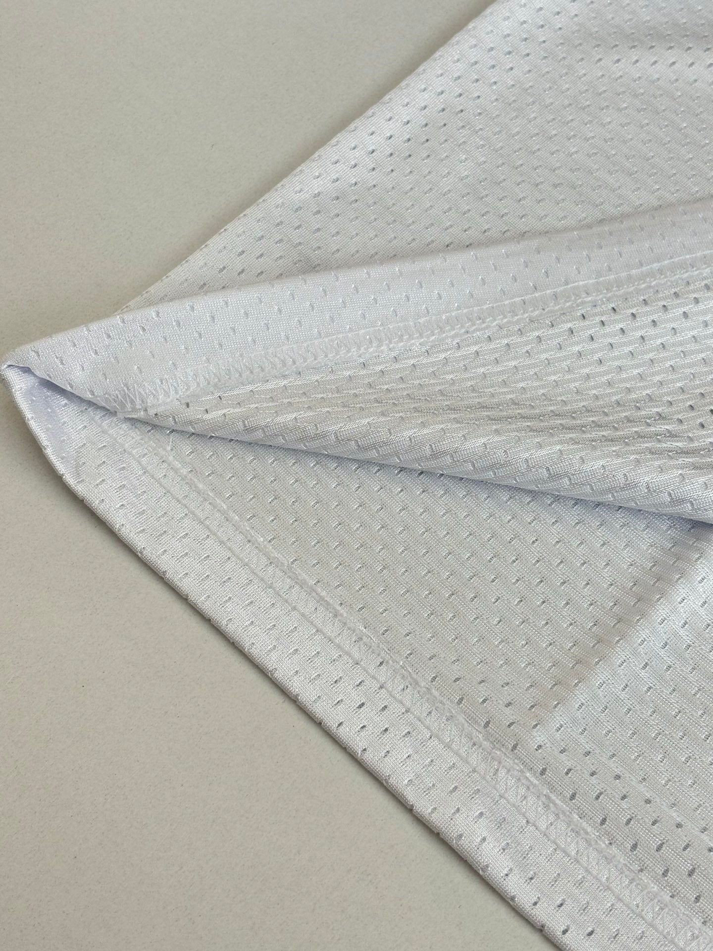 White long-sleeve jersey fabric close-up with subtle textured pattern