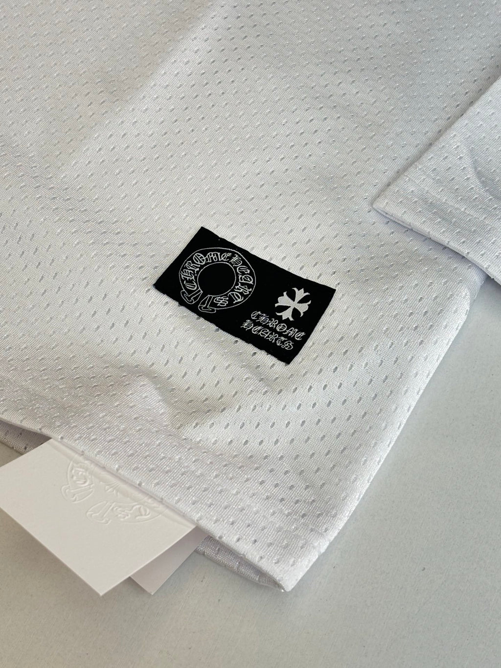 White long-sleeve jersey sleeve detail with black brand tag