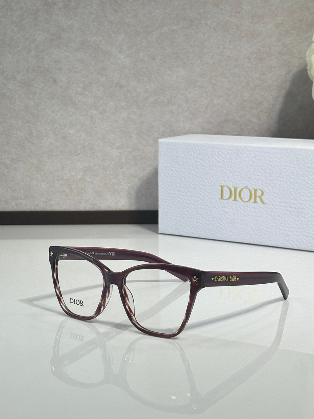 Burgundy eyeglass frames with clear lenses and logo on temple