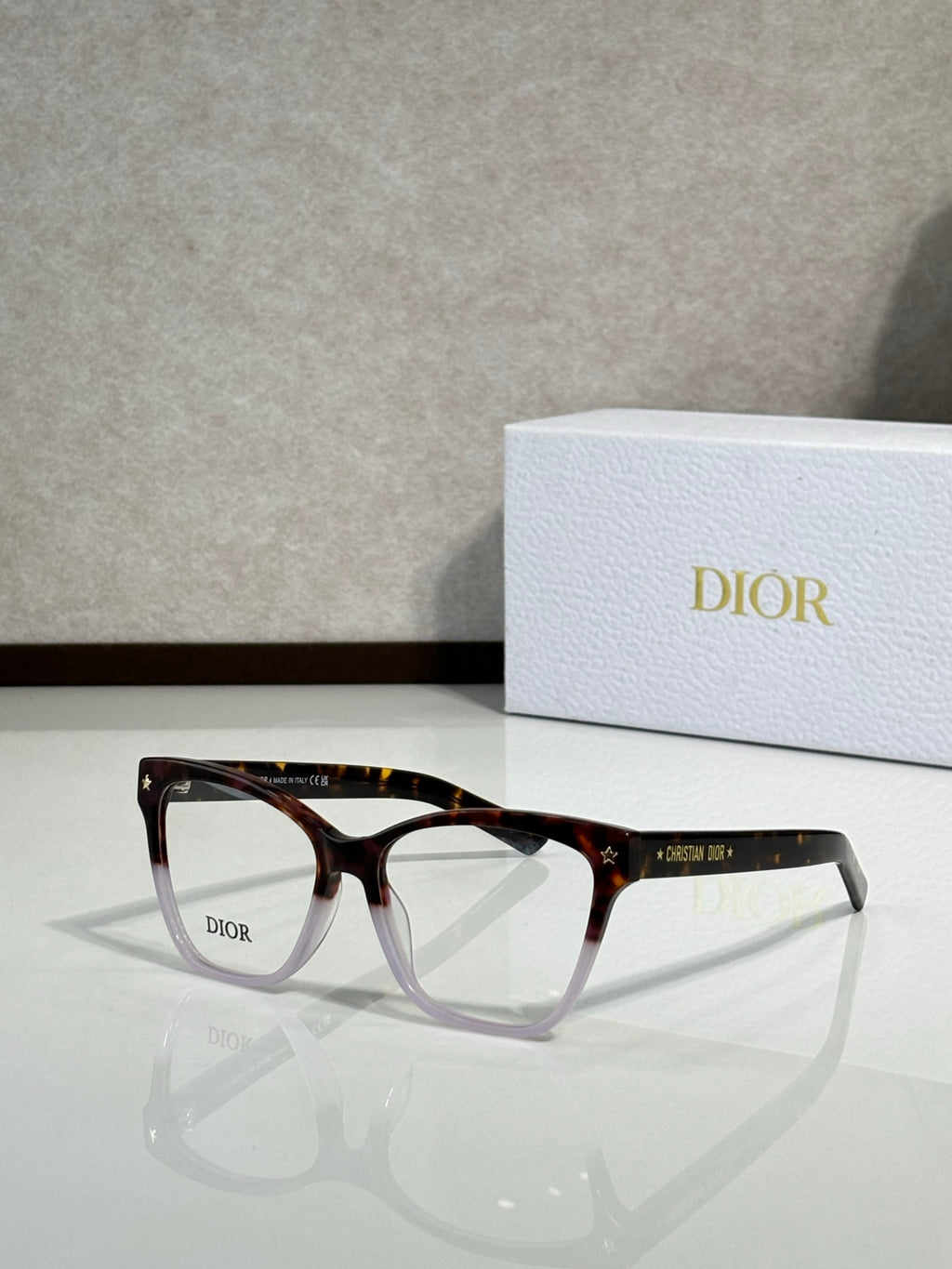 Brown tortoiseshell eyeglass frames with clear lenses and logo on temple
