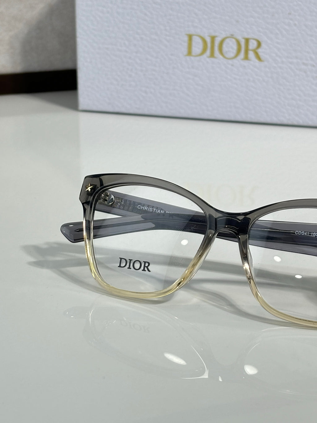 Blue eyeglass frames with gold rims and Dior logo on lens