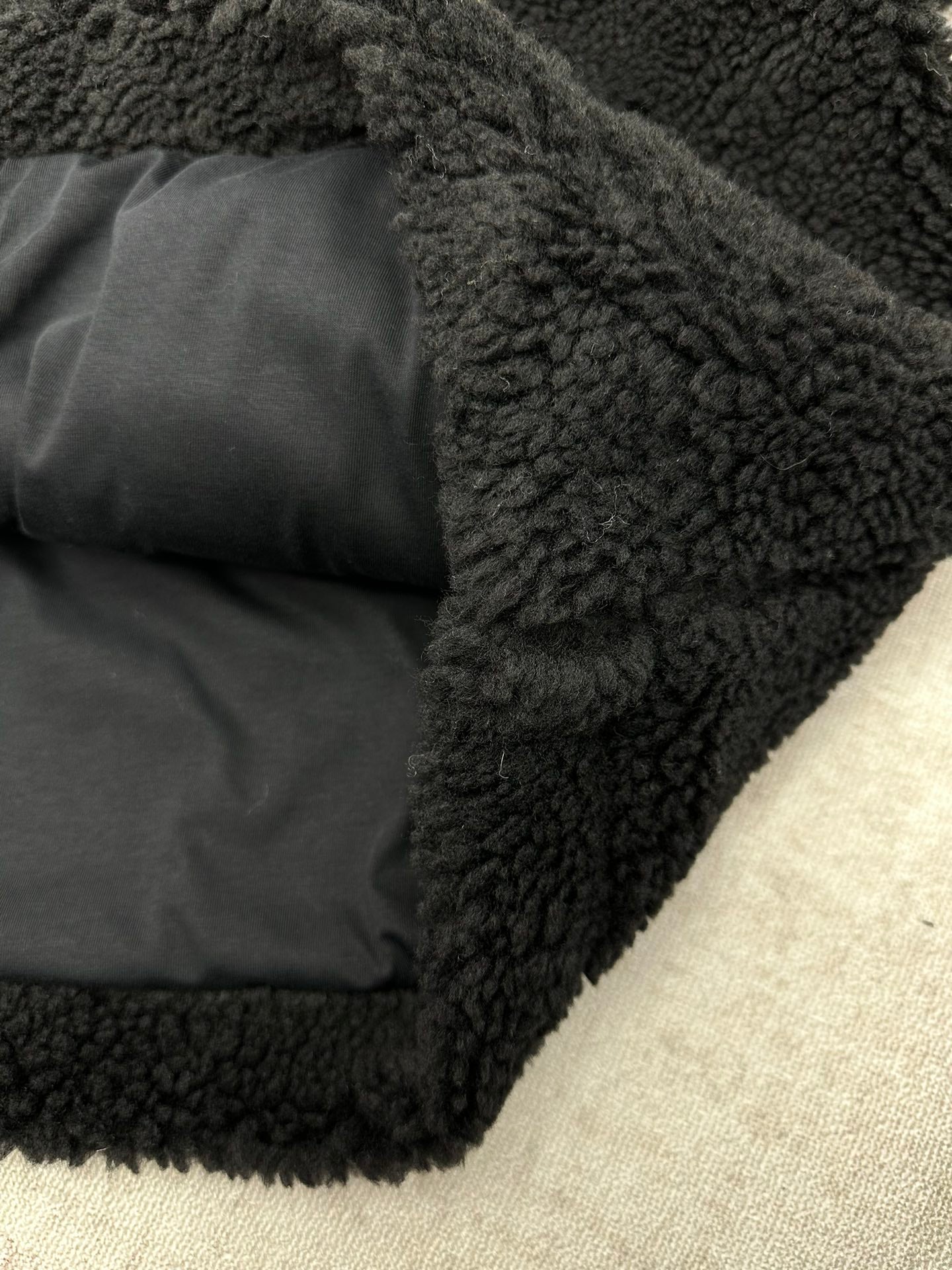 Black fleece jacket with gray lining and folded interior pocket