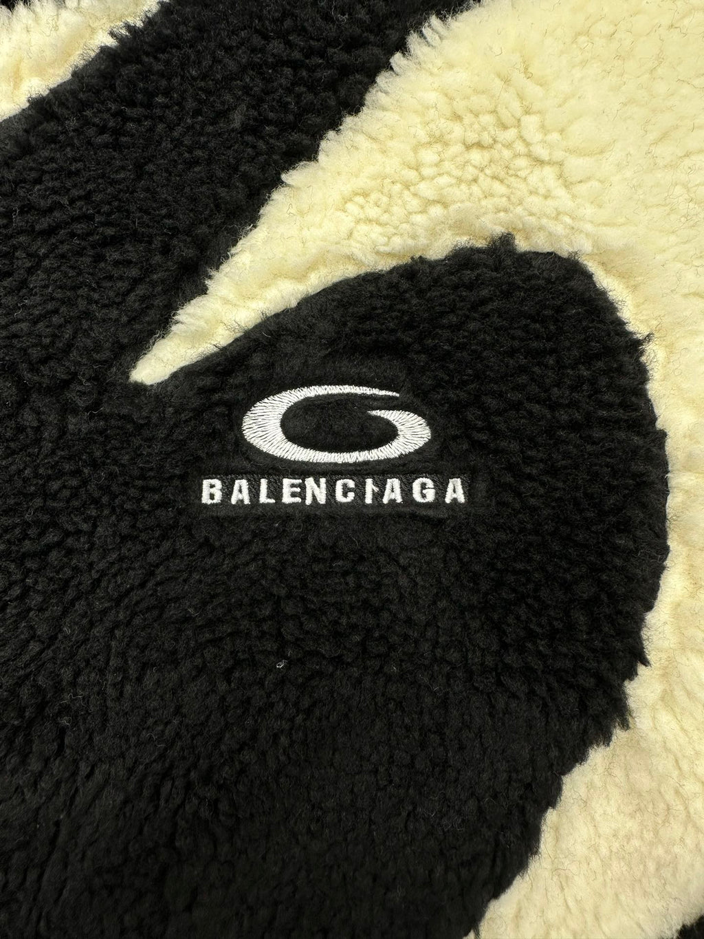 Black fleece jacket front with Balenciaga oval logo on off-white trim