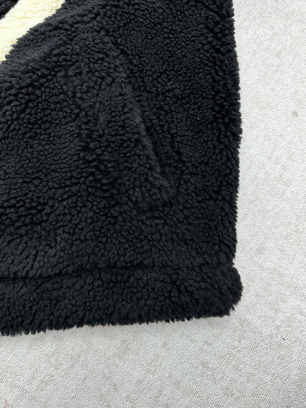 Black fleece jacket sleeve and hem with plush teddy texture