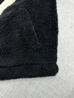 Black fleece jacket sleeve and hem with plush teddy texture