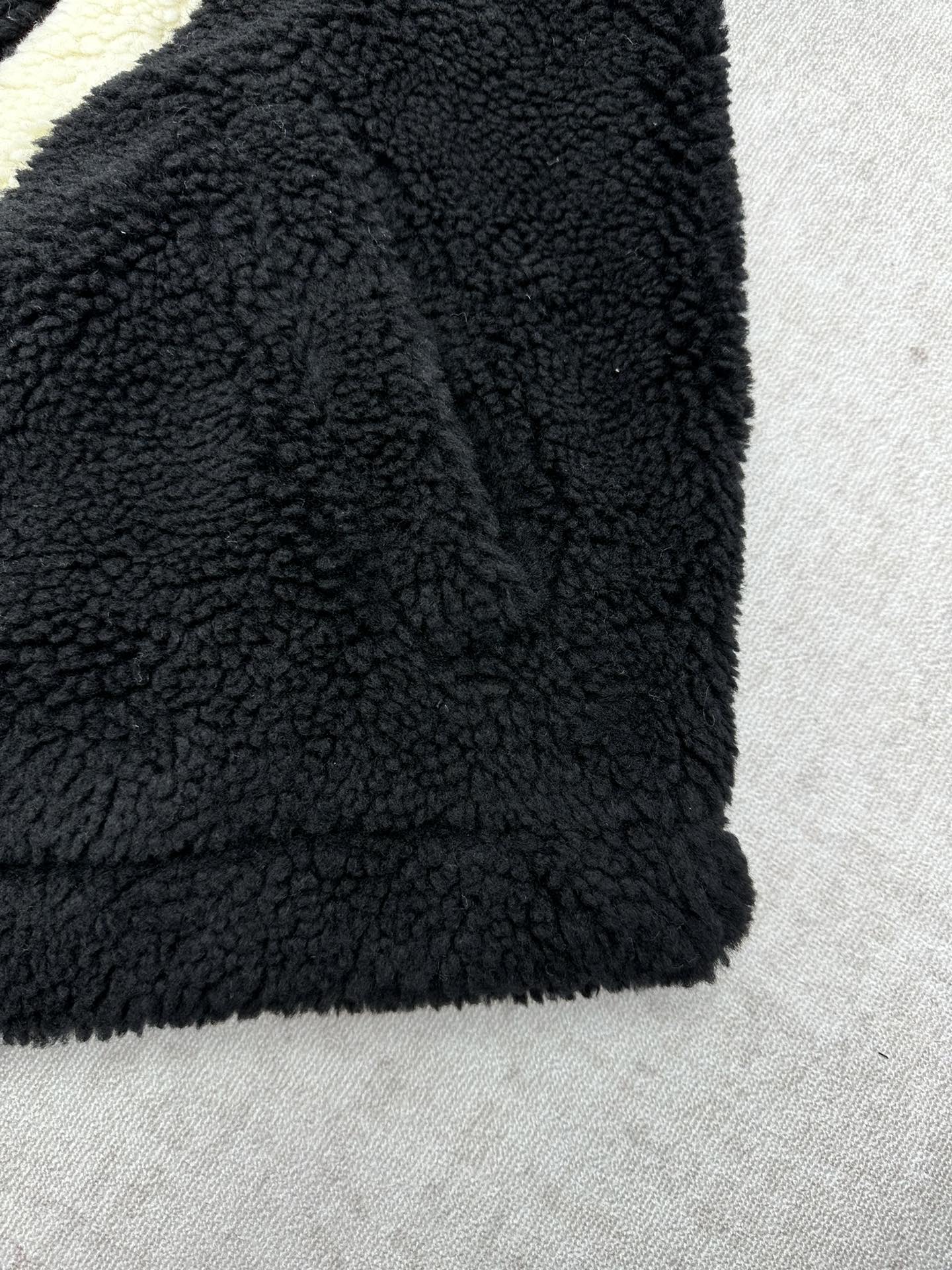 Black fleece jacket sleeve and hem with plush teddy texture