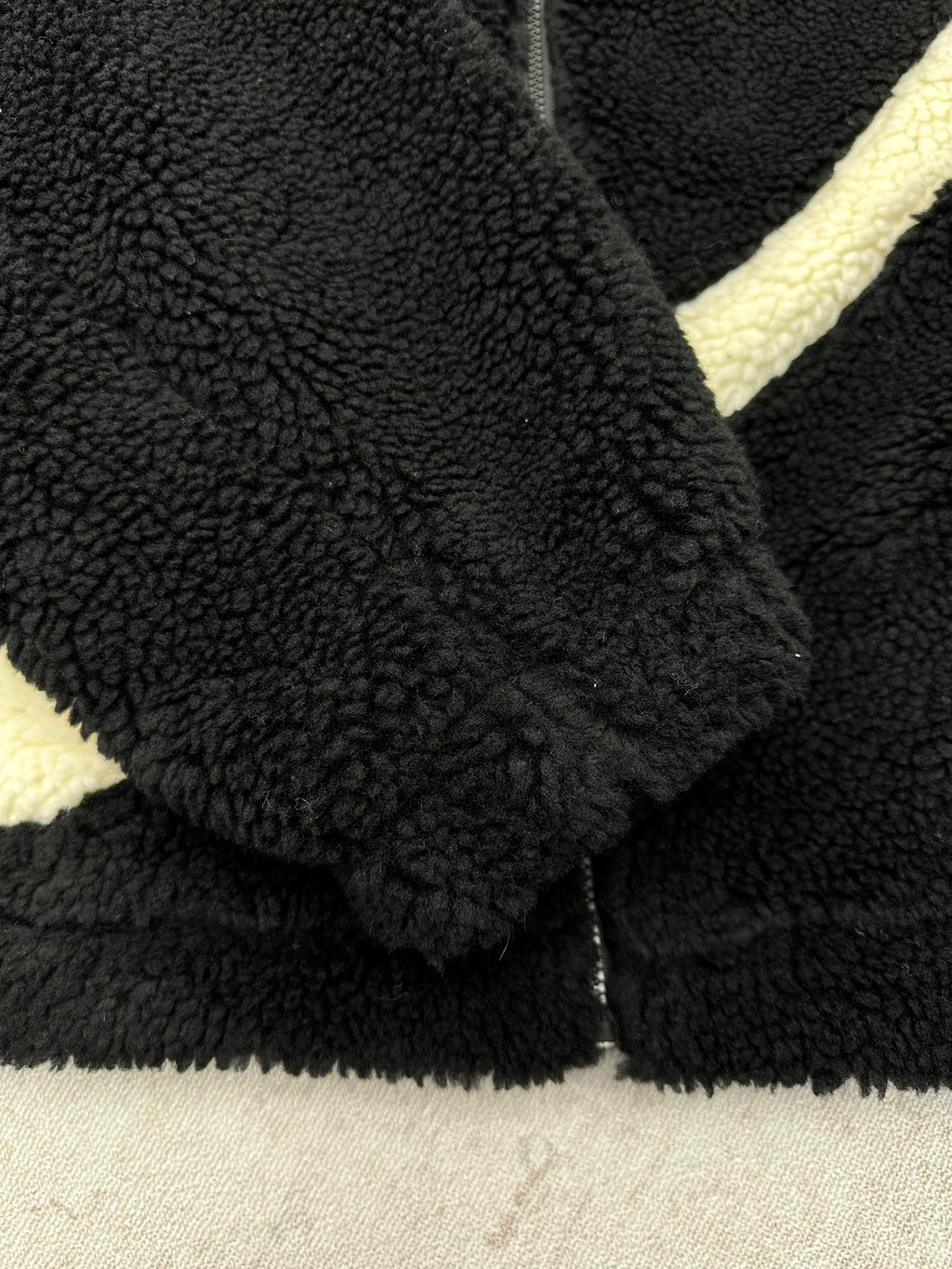 Black fleece jacket cuff and button detail with off-white trim