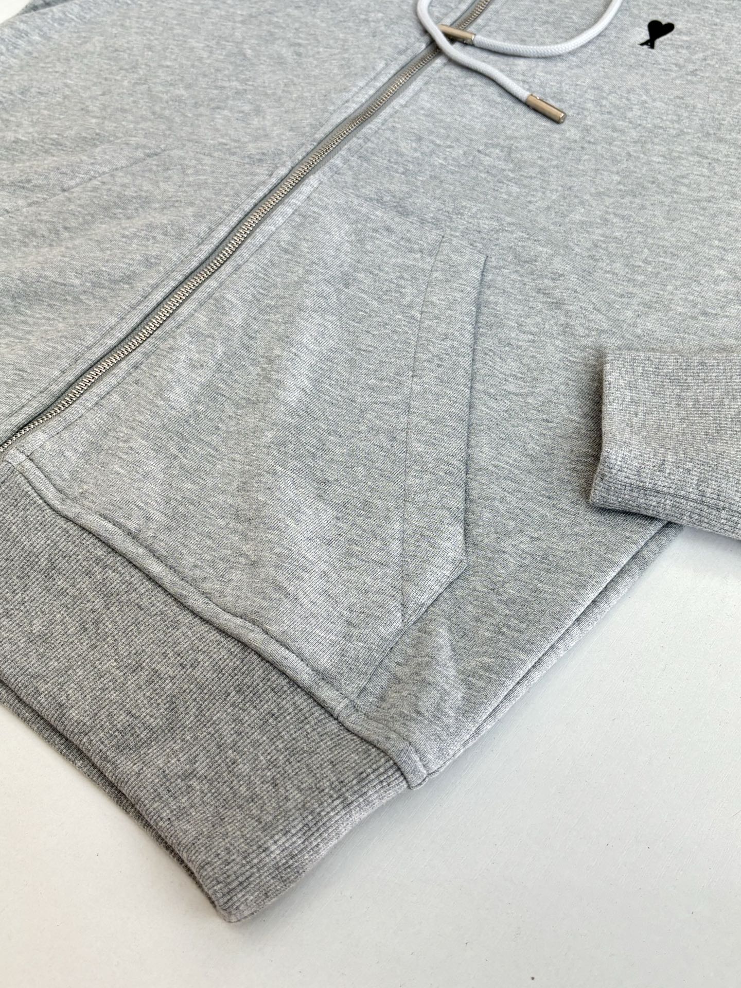 Amiri hoodie close-up showing metal zipper and gray drawcord inside hood
