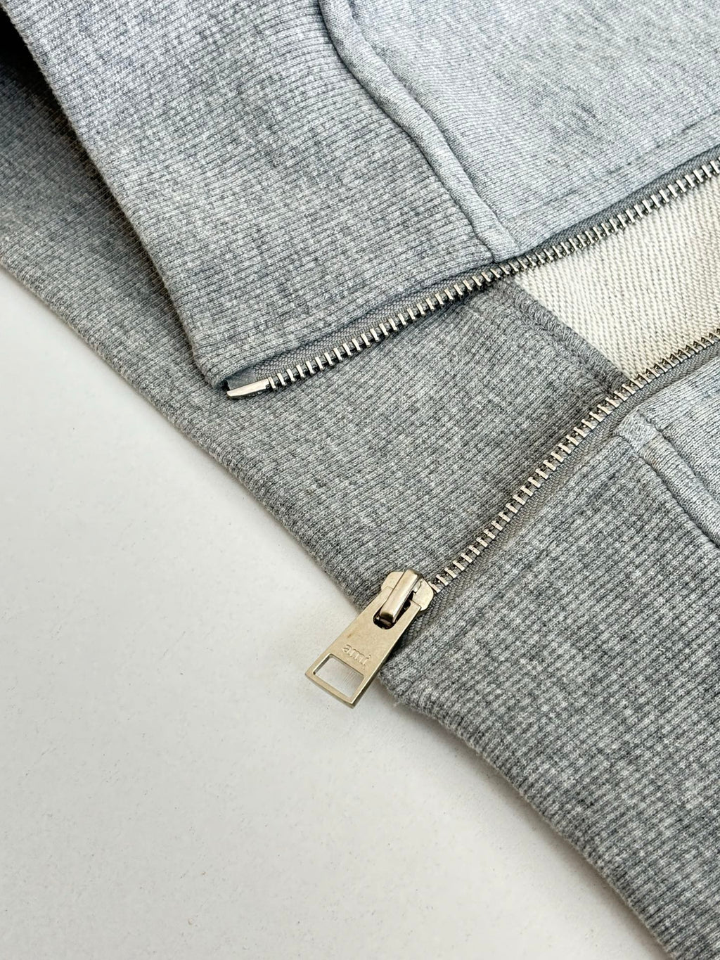 Amiri hoodie close-up of silver zipper pull and metal slider on light gray knit