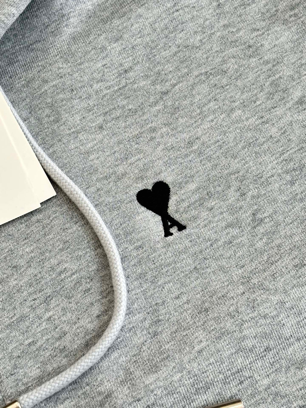 Amiri hoodie fabric close-up with small black silhouette emblem on chest