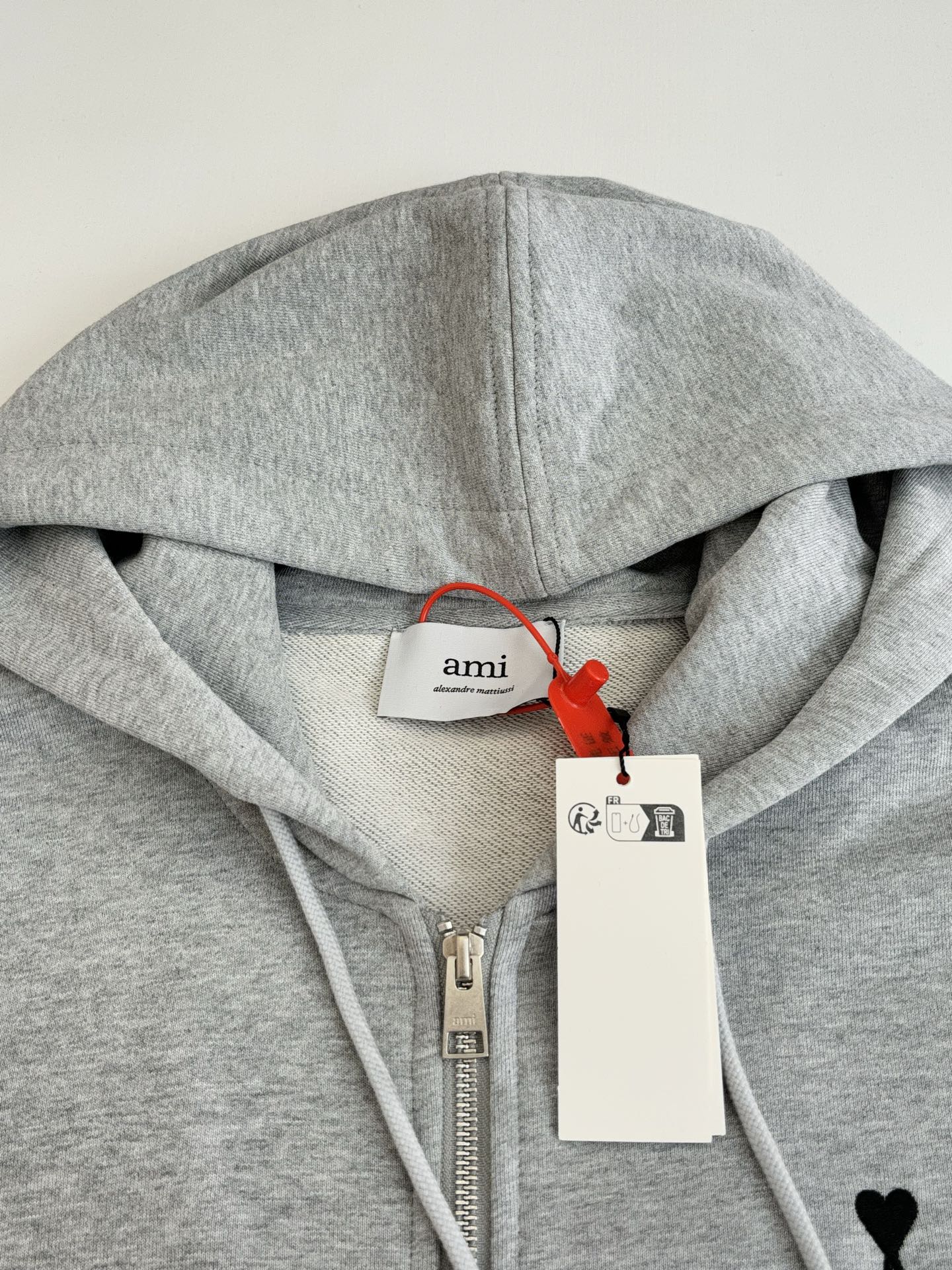 Amiri light gray hoodie neckline close-up with brand patch and hood drawstrings