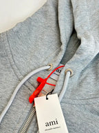 Amiri hoodie close-up of zipper, hood drawcord, and red tag with brand label