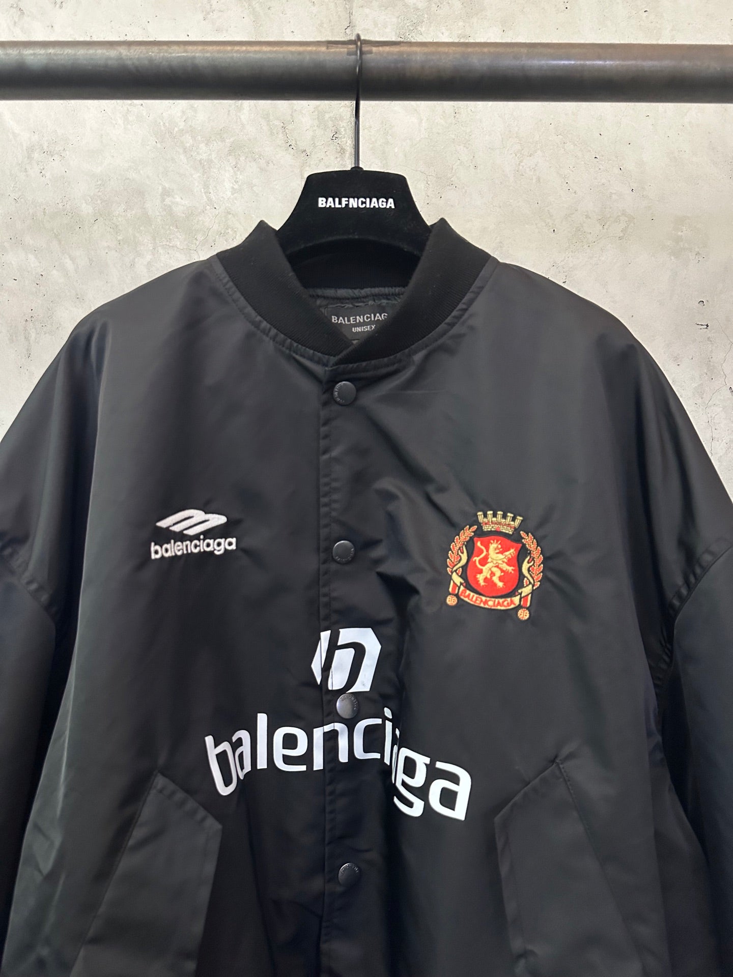 Balenciaga black bomber jacket with crest patch, Balenciaga logo, and button placket