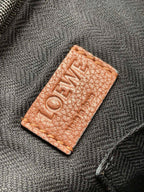 Embossed logo leather patch on bag strap in tan lettering on brown