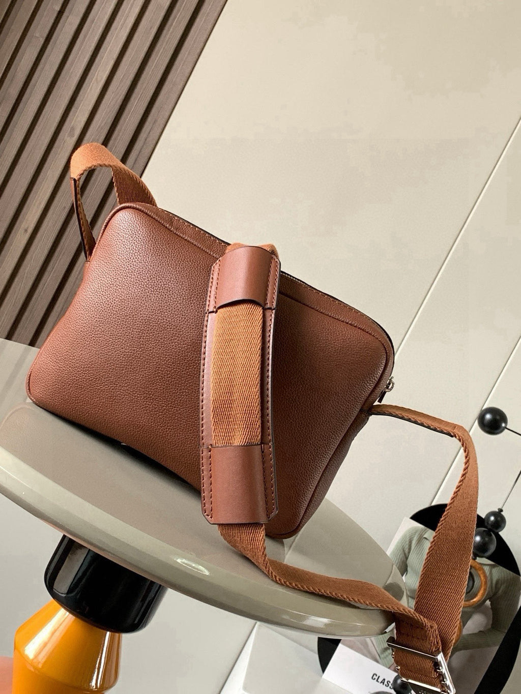 Leather crossbody bag with front flap, side panel straps, and metal buckle