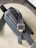 Gray leather crossbody bag with top zipper and adjustable strap with buckle