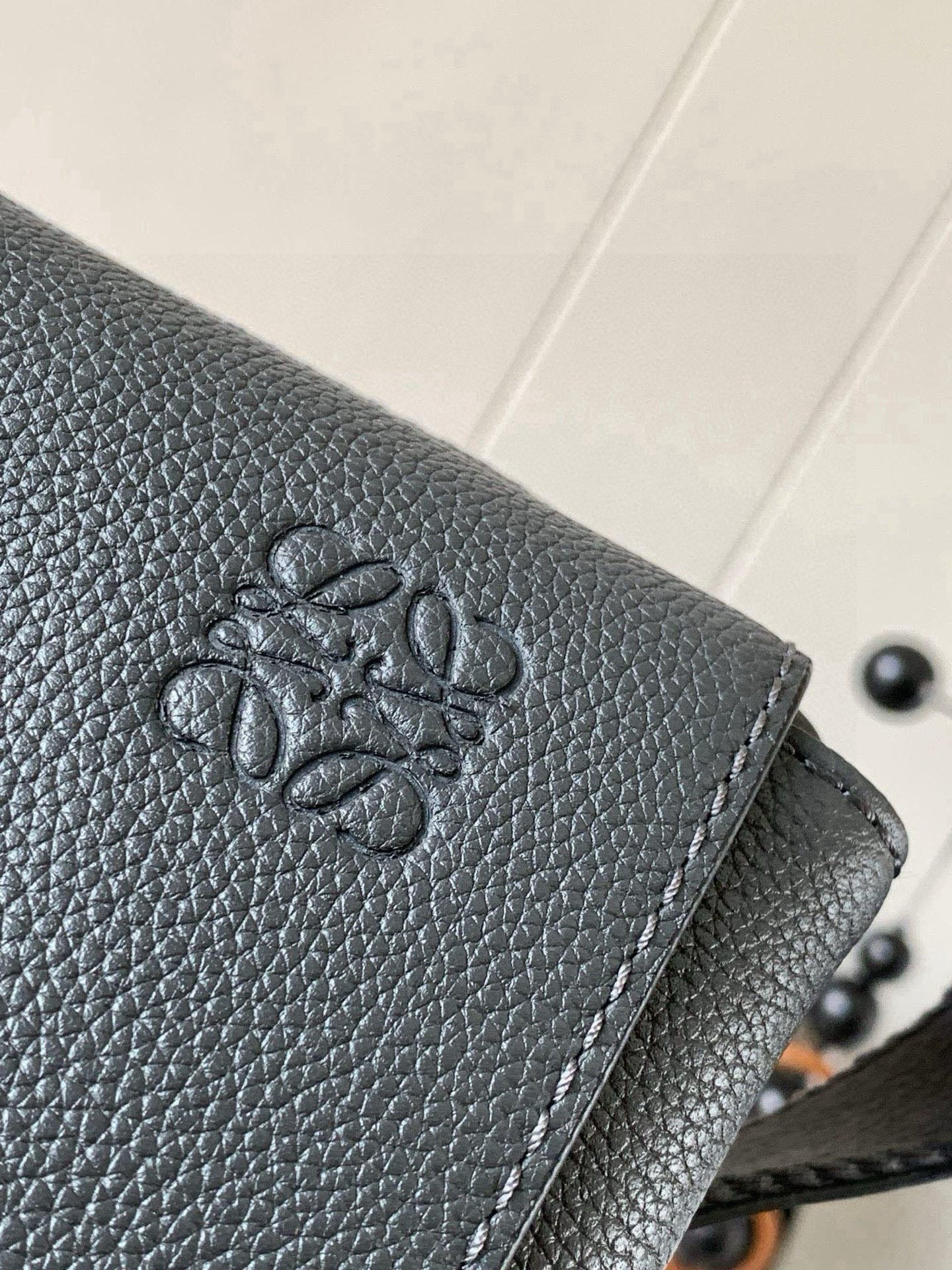 Gray leather flap with embossed logo detail and stitched edge