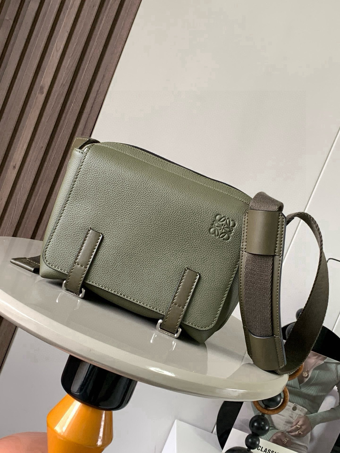 Loewe bag in sage green pebbled leather with flap, buckles, and crossbody strap