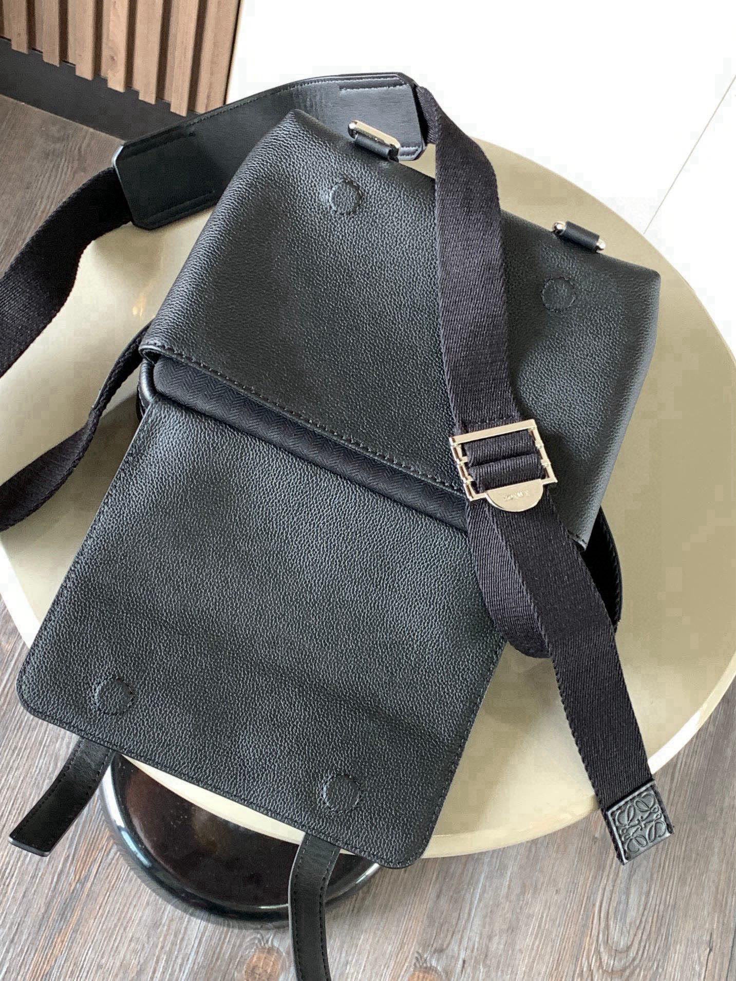Dark leather small backpack-style bag with metal buckles and shoulder straps